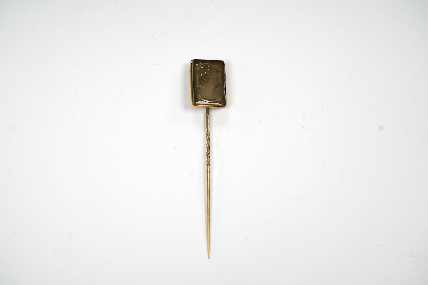 A yellow metal and cameo hardstone set stick pin, 88mm, gross weight 6.9 grams. Condition - poor to fair